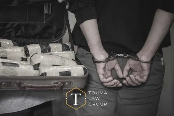 un hombre con las manos esposadas a la espalda junto a una bolsa de paquetes de drogas